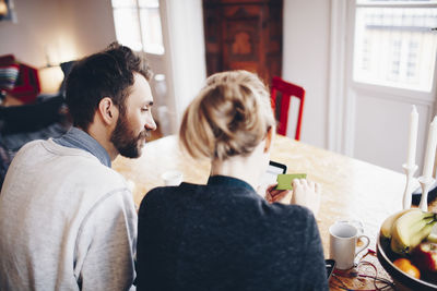 High angle view of couple shopping online from laptop and credit card at home