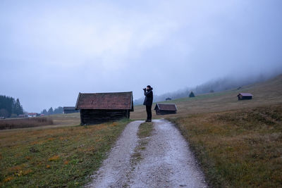 Rear view of man standing on field against sky