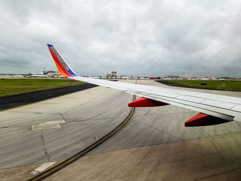 Airplane flying over airport runway against sky