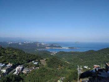 High angle view of townscape by sea against blue sky