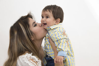 Side view of happy mother and daughter against white background