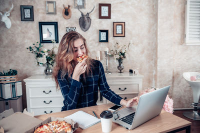 Woman using mobile phone while sitting on table