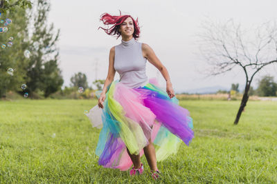 Woman dancing on field against trees