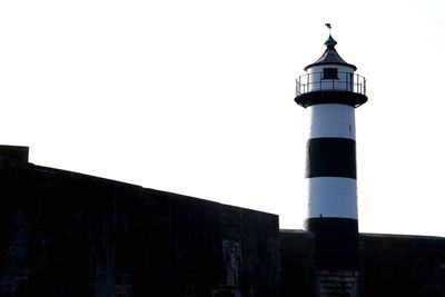 Low angle view of lighthouse against buildings against clear sky