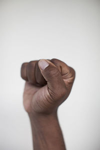 Cropped hand of man clenching fist against white wall at home