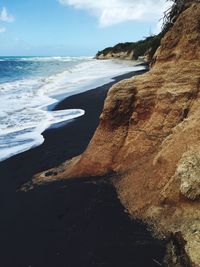 Scenic view of black sand beach against sky