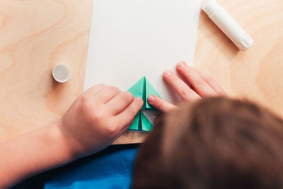 High angle view of man holding paper with hand on table