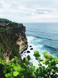 Scenic view of rocks by sea against sky