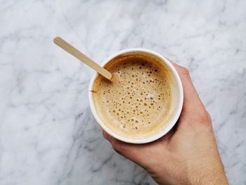 High angle view of hand holding coffee cup on table