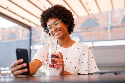 Smiling woman using mobile phone at table