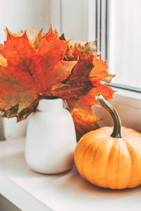 Autumn home decoration on the window using dry leaves and pumpkin