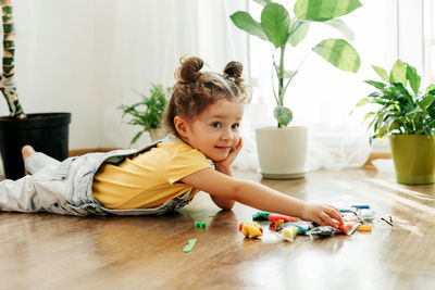 A charming little girl sculpts from colored plasticine on the floor. home schooling