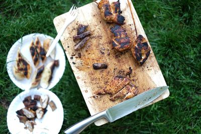 Directly above shot of grilled meat on cutting board with knife and fork