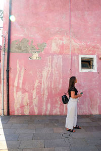 Woman standing on footpath against building