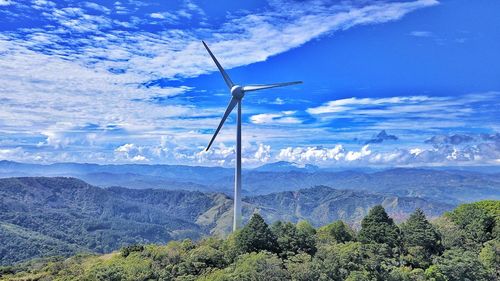 Wind turbines on landscape against sky