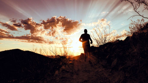 Silhouette man standing on land against sky during sunset