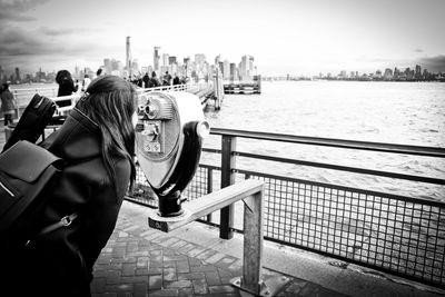 People looking at city by river against sky