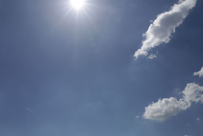 Low angle view of sunlight streaming through clouds