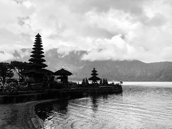 Traditional building by lake against sky