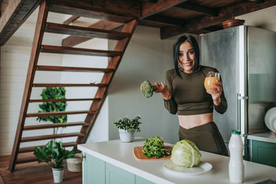 Portrait of smiling woman standing by potted plants