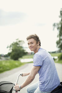 Portrait of young man on bicycle at countryside