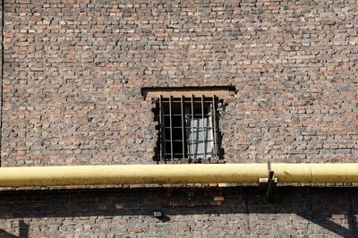 Yellow pipe on brick wall during sunny day