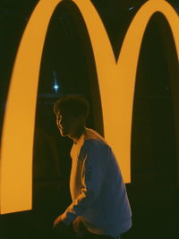 Side view of man looking at illuminated lamp