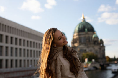 Smiling young woman standing against buildings in city