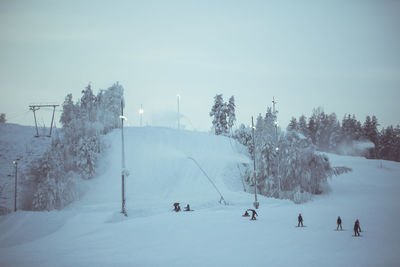 People skiing and snowboarding on snow covered land