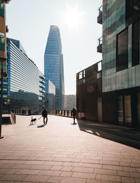 People walking on modern buildings in city against sky