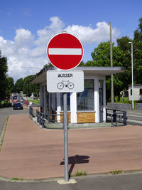 Road sign by street against sky