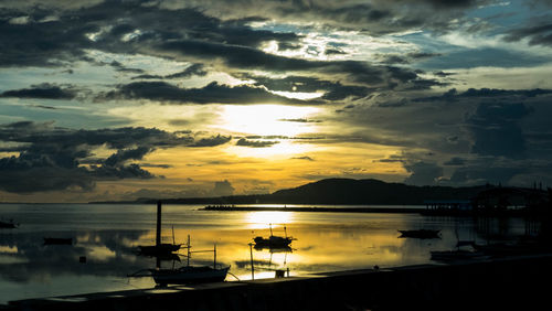 Boats moored at harbor during sunset