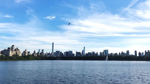 Cityscape by lake against sky