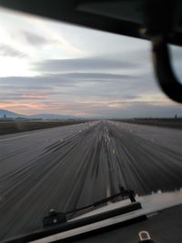 Road seen through car windshield during sunset