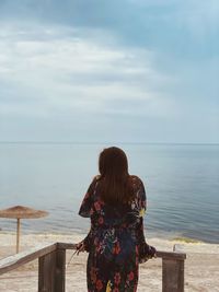 Rear view of woman looking at sea against sky