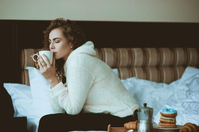Contemplative woman having coffee in bedroom