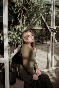 Side view of thoughtful woman sitting in greenhouse