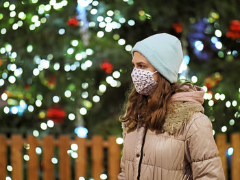 Rear view of woman standing against illuminated christmas tree