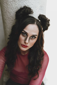 Portrait of woman sitting by wall outdoors