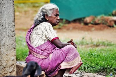 Side view of woman sitting on field