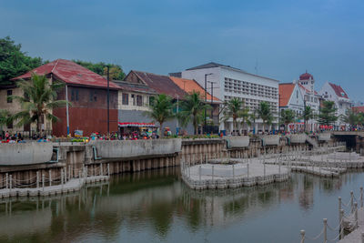 Buildings by river against sky in jakarta 