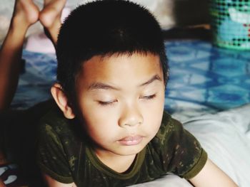 Close-up of sleepy boy lying on bed at home