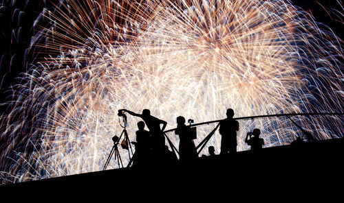 Silhouette people with fireworks at night