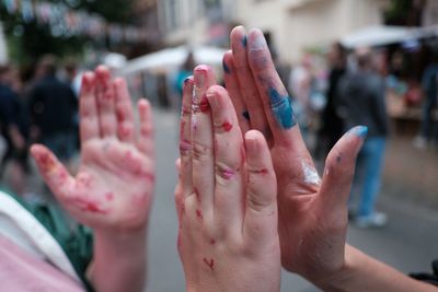 Cropped hands of messy friends high-fiving on footpath in city