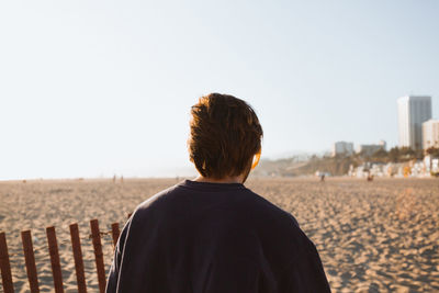 Rear view of man looking at sea against clear sky