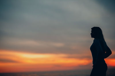 Silhouette woman standing against sky during sunset