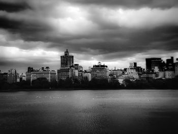 City at waterfront against cloudy sky