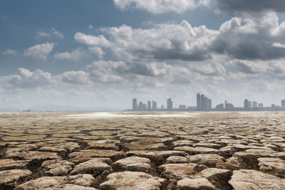 Cracked land against cityscape