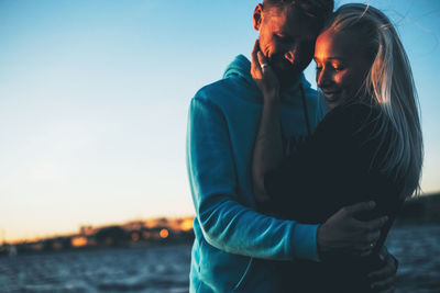 Couple embracing against sea during sunset