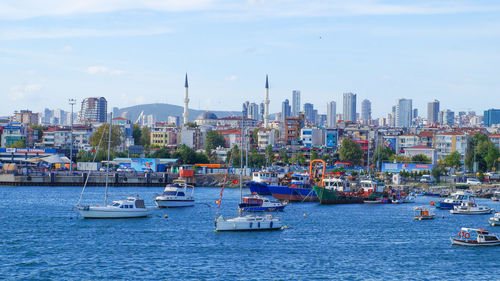 Sailboats in sea against buildings in city